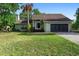 Charming single-story home with a lush green lawn, mature trees, and a two-car garage at 21343 Reindeer Rd, Christmas, FL 32709