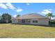 Back exterior view showcasing a large backyard and sliding glass doors leading to the living area at 23533 Valderama Ln, Sorrento, FL 32776
