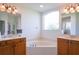 Bright bathroom featuring a soaking tub with a large frosted window and double vanity sinks at 23533 Valderama Ln, Sorrento, FL 32776