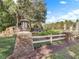 Community entrance featuring stone pillars, white fence, and attractive landscaping at 23533 Valderama Ln, Sorrento, FL 32776