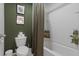 Green bathroom with toilet, shower with curtain, and white accents at 4054 Silverstream Ter, Sanford, FL 32771