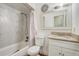 Bright bathroom featuring a shower-tub combo with marble-look tile, vanity with sink, and decorative mirror at 4201 Chantelle Rd, Orlando, FL 32808
