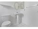 Classic white bathroom featuring a pedestal sink, toilet, round mirror, and a tiled floor at 445 Cottonwood Dr, Altamonte Springs, FL 32714