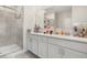 Bright bathroom with double sinks, white cabinetry, and a glass-enclosed shower at 4459 Bluff Oak Loop, Kissimmee, FL 34746