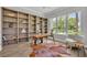 A home office offers natural light from a large window, custom bookshelves, and modern decor at 731 Williams Dr, Winter Park, FL 32789