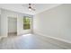 A bright, minimalist bedroom with a large window, gray wood floors, and neutral walls at 8908 Legacy Ct # 303, Kissimmee, FL 34747