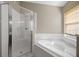 Bathroom showcasing a glass-enclosed shower and a corner soaking tub below a window with blinds at 9545 Southern Garden Cir, Altamonte Springs, FL 32714