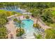 Aerial view showcasing a large community pool, surrounded by palm trees and lush landscaping, and a peaceful lake at 1031 Marcello Blvd, Kissimmee, FL 34746