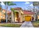 Charming single-Gathering home featuring a red tile roof, yellow garage, and mature palm trees at 1031 Marcello Blvd, Kissimmee, FL 34746