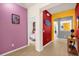 Hallway featuring vibrant red, yellow, and pink walls, and a view of two themed bedrooms at 1031 Marcello Blvd, Kissimmee, FL 34746