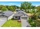 Aerial view of a home with a gray roof, white siding, gray brick driveway, green lawn, and mature trees at 1109 Naples Dr, Orlando, FL 32804