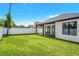 A spacious backyard with a covered patio, a large lawn, a privacy fence, and sliding glass doors to the house at 1109 Naples Dr, Orlando, FL 32804