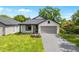 Charming home featuring a gray roof, white siding, brick driveway, manicured lawn, and a two-car garage at 1109 Naples Dr, Orlando, FL 32804