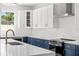 Modern kitchen featuring white and blue cabinetry, stainless steel appliances, and a stylish geometric backsplash at 1109 Naples Dr, Orlando, FL 32804