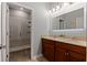 Bathroom featuring double sinks with dark cabinets, a decorative mirror and a walk-in shower at 11927 Charades St, Orlando, FL 32832