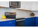 Modern kitchen featuring stainless steel appliances, white cabinets and vibrant blue lower cabinetry at 11927 Charades St, Orlando, FL 32832