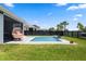 Backyard pool with a water feature, modern chair, black fence, and green grass at 11927 Charades St, Orlando, FL 32832