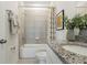 Bright bathroom featuring a shower-tub combo with stylish granite countertop and modern fixtures at 1240 Blue Daze Ln, Eustis, FL 32726