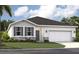 Charming single-story home with a two-car garage, white exterior, and well-manicured lawn at 1240 Blue Daze Ln, Eustis, FL 32726