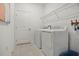 Clean laundry room with a white washer and dryer, tile flooring, a storage shelf, and a hanging rack at 1240 Blue Daze Ln, Eustis, FL 32726