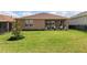 Expansive backyard features a covered patio with neutral exterior finishes, well-maintained lawn and lush plantings for outdoor enjoyment at 125 Silver Maple Rd, Groveland, FL 34736