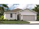Charming single-story home featuring neutral stucco, a two car garage and tropical landscaping at 1251 Blue Daze Ln, Eustis, FL 32726