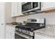 Kitchen features stainless steel range and microwave, white cabinets, and granite countertops at 1252 Blue Daze Ln, Eustis, FL 32726