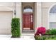 Close up of front door framed by green bushes and pink flowers at 128 Brushcreek Dr, Sanford, FL 32771