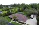 Expansive ranch-style home with a brown roof, set on a lush green lawn, surrounded by mature trees and screened pool at 15305 Shady Ln, Tavares, FL 32778