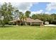 Exterior featuring a well-manicured lawn, mature landscaping, and attached garage at 15305 Shady Ln, Tavares, FL 32778