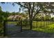 Gated home showcasing a long driveway, mature trees, and well-maintained landscaping at 15305 Shady Ln, Tavares, FL 32778