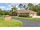 Exterior view of home, manicured hedges, palm tree, lush lawn, long driveway, and three-car garage at 15305 Shady Ln, Tavares, FL 32778