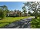 Exterior of home featuring a well-manicured lawn, mature trees, and a long paved driveway at 15305 Shady Ln, Tavares, FL 32778