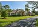 Exterior of a home with mature landscaping, a palm tree, and a long paved driveway at 15305 Shady Ln, Tavares, FL 32778