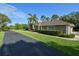 Exterior of a charming home featuring a well-manicured lawn, palm tree, and a paved driveway at 15305 Shady Ln, Tavares, FL 32778
