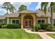 Charming home featuring a grand arched entryway, manicured landscaping, and a welcoming facade at 15305 Shady Ln, Tavares, FL 32778