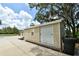 Exterior view of a small outbuilding with a roll-up door and a concrete driveway at 15305 Shady Ln, Tavares, FL 32778