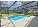 Kidney-shaped pool under a screened enclosure surrounded by well-manicured lawn at 15305 Shady Ln, Tavares, FL 32778