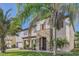 Beautiful two-story home with stone accents, a manicured lawn, and lush landscaping with mature palm trees at 15465 Heron Hideaway Cir, Winter Garden, FL 34787
