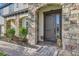 Inviting front entrance with a stone facade, arched entryway, and meticulously landscaped garden beds at 15465 Heron Hideaway Cir, Winter Garden, FL 34787