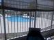 Community swimming pool with lounge chairs and a surrounding fence visible from the screened-in patio at 1621 Emily Ct, Kissimmee, FL 34744