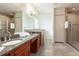 Well-lit bathroom featuring double sinks, granite countertops, a glass-enclosed shower, and linen closet at 18920 Overton St, Orlando, FL 32833