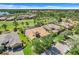 Aerial view of a tile roof home on a golf course with pristine landscaping, and community lake at 196 Torino Ln, Kissimmee, FL 34759