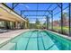 Pool with a built in hot tub, screened in by beautiful foliage and blue skies at 196 Torino Ln, Kissimmee, FL 34759