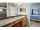 Bright bathroom featuring a granite countertop vanity, wood cabinets, and a view into the main bedroom at 2302 Edmonton Ct, Clermont, FL 34711