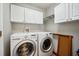 Bright laundry room features a full-size washer and dryer with upper cabinets for storage at 2302 Edmonton Ct, Clermont, FL 34711