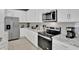 Close-up of a kitchen featuring stainless steel appliances, white cabinetry, and granite countertops at 2382 Zaballina Pl, Kissimmee, FL 34747