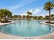 A large swimming pool with beach chairs and palm trees under a blue sky with white clouds at 2382 Zaballina Pl, Kissimmee, FL 34747