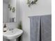 Clean half bath features a pedestal sink, modern faucet, decorative mirror and wreath and soft grey towel at 242 Milestone Dr, Haines City, FL 33844