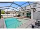 Beautiful screened pool area featuring tanning ledge, outdoor kitchen, and ample lounge space at 242 Milestone Dr, Haines City, FL 33844